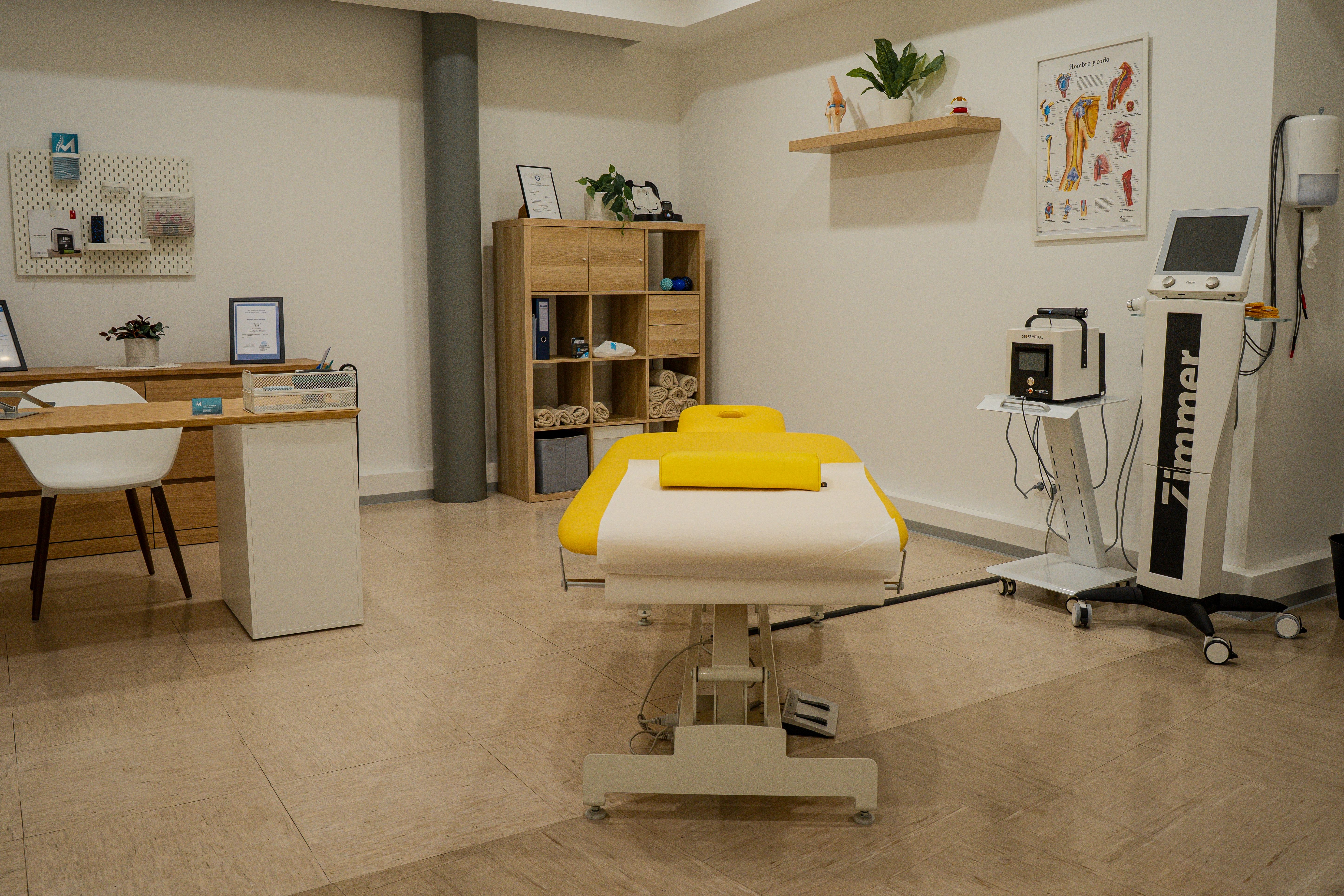 Modern treatment room with a bright yellow examination bed and various medical equipment.