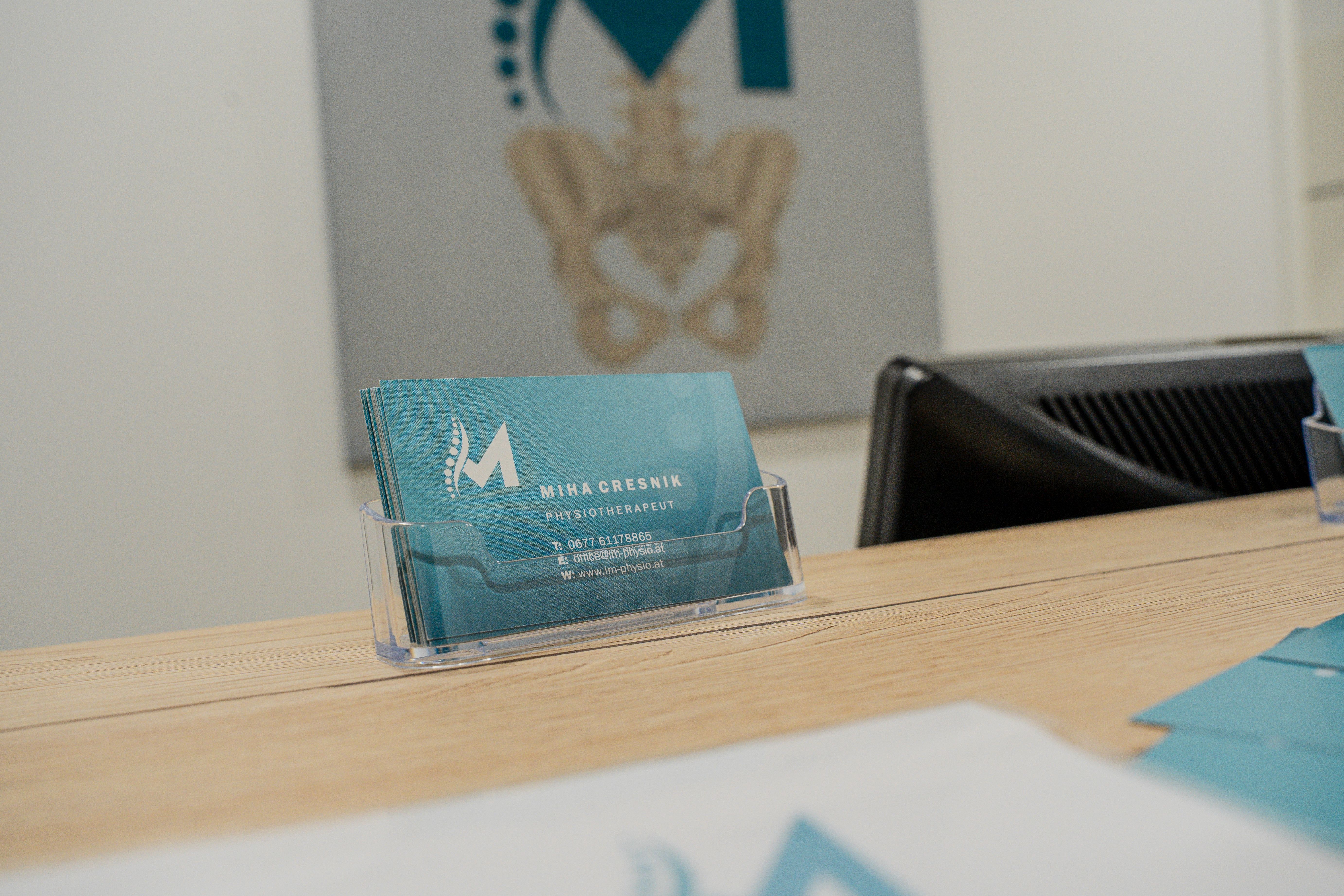 Business card for Mora Research on a wooden counter with a skeletal pelvis logo in background.
